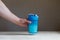 Hand holding plastic shaker with protein shake and glass on table. Man\'s fist holding the post workout chocolate whey protein sha