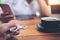 A hand holding and playing metal silver color fidget spinner with coffee cups and people using mobile phone