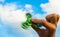 Hand holding popular green fidget spinner on sky background with copy space.