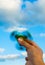 Hand holding popular green fidget spinner on sky background with copy space.