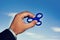 Hand holding popular green fidget spinner toy on sky background with copy space.