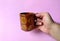 Hand holding a porcelain cup with Guatemalan coffee on pink background. drink concept