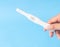 Hand holding pregnancy test with blue background, health care an