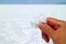 Hand holding pure white natural salt crystals with blurred Salar de Uyuni Salt Flats of Bolivia in background