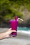 Hand holding purple cocktail in glass decorated with plastic straws  and piece of dragon fruit on the sandy tropical beach