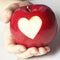 Hand holding red apple with heart