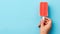 Hand Holding Red Ice Cream Bar on Blue Minimalistic Background AI Generated