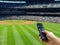 Hand holding remote control on baseball match TV