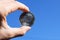 Hand holding silver Dash coin on blue sky background