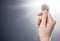 Hand holding a silver IOTA coin on a gently lit background