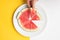 Hand holding slice of watermelon over split color background
