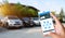 Hand holding smart phone and application dashboard with blur car parking background