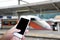 Hand holding smart phone over blur train station background