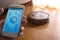 Hand holding smartphone with application control robot vacuum cleaner