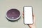 Hand holding smartphone with blanking screen for control robotic vacuum cleaner . Smart life technology concepts
