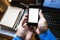 Hand holding smartphone on messy working table