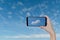 Hand holding smartphone for take photo a single cloud over blue sky