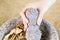 Hand holding stone pestle in bowl filled with Chinese Herbs