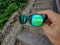 The hand holding sunglasses, green lens