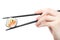 Hand holding sushi roll with black chopsticks