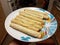 Hand holding taquitos on plate in kitchen