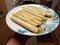 Hand holding taquitos on plate in kitchen