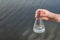 hand holding test tube for analyses with water on the background of the reservoir, the concept of water purity, pollution of water