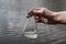 hand holding test tube for analyses with water on the background of the reservoir, the concept of water purity, pollution of water