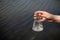 hand holding test tube for analyses with water on the background of the reservoir, the concept of water purity, pollution of water