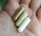 Hand holding three vitamin supplements capsules