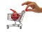 Hand holding a tiny shopping cart with a red decoration Christmas ball