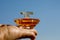 Hand holding transparent glass perfume bottle. travel size vial against blue sky