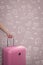 Hand holding traveler pink suitcase or cabin size luggage with h