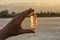 A hand holding up a beautiful quartz crystal outdoors in the sun