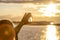 A hand holding up a beautiful quartz crystal outdoors in the sun