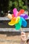 A hand holding up a childs milti coloured rainbow windmill