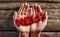 A hand is holding up red word text HELP on wooden panel background.