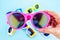 Hand holding vivid pink sunglasses with blur group of glasses at