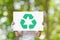 Hand holding white board with recycle logo over green nature