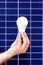 Hand holding white bulb against solar panel, solar station. Idea concept of alternative energy, technology, environment, ecology.