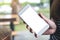 A hand holding white mobile phone with blank desktop screen with blur raining background