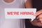 Hand holding white talk bubble and showing a we\'re hiring wordin