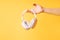 Hand holding white wireless headphones against yellow background