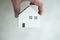 Hand holding white wooden mockup home. The concept of real estate loan insurance buys and sells the home