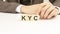 hand holding wooden cube blocks with text kyc - know your client - on white table background. financial, marketing and