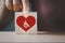 Hand holding wooden cubes with disabled people in red heart symbols,  aged senior nurse care, disabilities health care