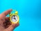 Hand holding yellow alarm clock on a blue background