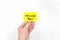 Hand holding a yellow welcome back note card. Back to work, office and school concept.