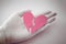Hand holds a broken heart. Grey and pink photo. Devorce and separation concept. Broken heart symbol. Paper heart. Relationship pro