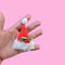 Hand holds Christmas santas hat on pastel pink background. Minim